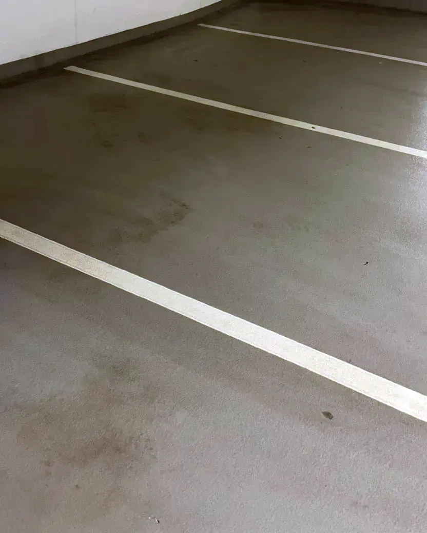Gereinigter Betonboden in einer Tiefgarage mit weißen Parkmarkierungen.